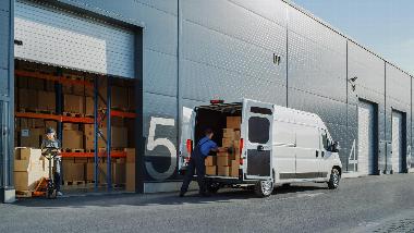 a person loading a white van from a warehouse